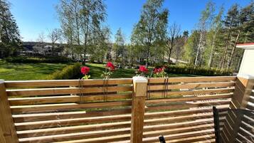 Une terrasse en bois offrant une vue sur une pelouse bien entretenue et des arbres.
