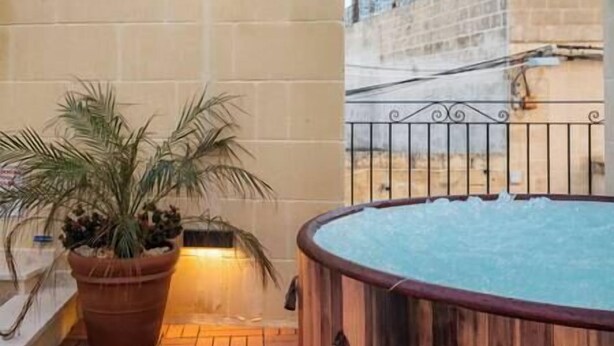 A hot tub on a tiled patio with a potted palm plant beside it. - Narcisa - Luxury House w/ Pool, Cinema & Hot Tub (Ix-XagÄ§ra)