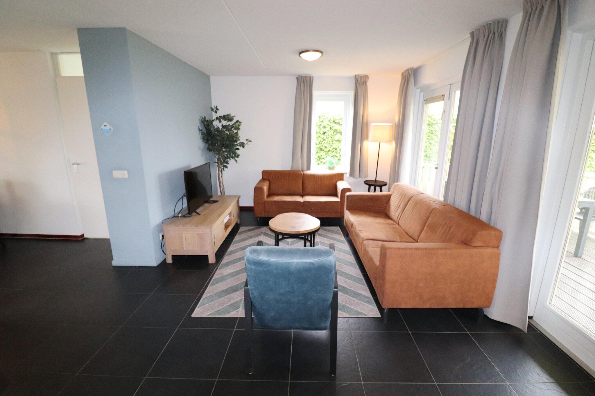 Een moderne woonkamer met een bank, fauteuil en een klein bijzettafeltje.