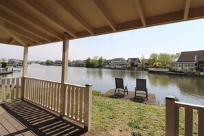 Eine überdachte Terrasse mit Blick auf einen ruhigen Fluss, zwei Stühle und ein Holzsteg.