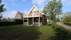 A two-story house with a balcony, a lawn, and a driveway. - Bungalow in Zuytland by Water and Nature (Simonshaven)