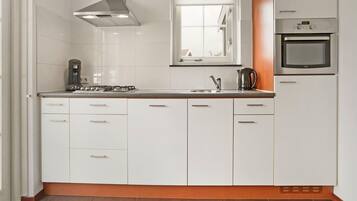 A modern kitchen with white cabinets, a gas stove, a coffee maker, and an oven.