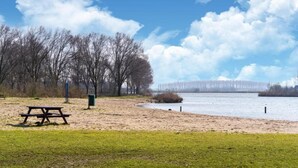 A lakeside park with a picnic table and benches, surrounded by trees and a clear sky. - Sun-Soaked Bungalow in Simonshaven (Simonshaven)