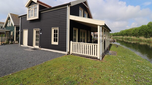 A two-story house with a porch, a small deck, and a river view. - Sun-Soaked Bungalow in Simonshaven (Simonshaven)