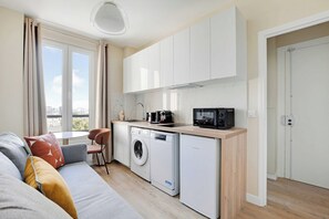 Ett kompakt kök med tvättmaskin, mikrovågsugn och diskho.