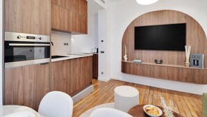 Une cuisine moderne avec des meubles en bois, un four encastré et un téléviseur à écran plat fixé à un mur en bois.