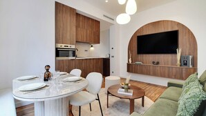 Une cuisine moderne avec des meubles en bois, un four encastré et un coin repas comprenant une table ronde et des chaises.