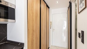 A modern kitchen with a built-in oven, wooden cabinets, and a marble countertop. - Large studio apartment with terrace and sea view (Cannes)