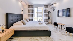 A modern bedroom with a large bed, a TV, and a balcony view. - Large studio apartment with terrace and sea view (Cannes)