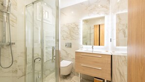 A modern bathroom with a glass shower enclosure, a toilet, and a vanity with a mirror. - Large studio apartment with terrace and sea view (Cannes)