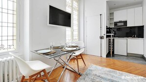 A modern kitchen with white cabinets, a black countertop, and a built-in microwave. - Charming studio - 3P - Le Marais (Paris)