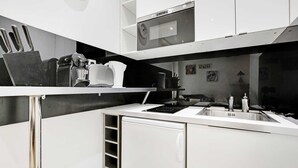 A modern kitchen with white cabinetry, a built-in espresso machine, and a sink. - Charming studio - 3P - Le Marais (Paris)