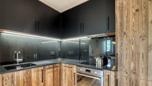 A modern kitchen with dark cabinets, a wooden countertop, and stainless steel appliances.