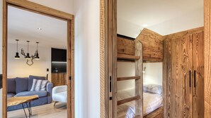 A modern room with a wooden wardrobe, a bed, a sofa, and a dining table.