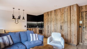 A modern living room with a blue sofa, a white armchair, and a wooden coffee table.