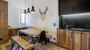 A modern kitchen with wooden cabinetry, a black backsplash, and pendant lighting.