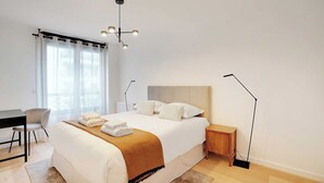 A modern bedroom with a large bed, a desk, and a chair. - Sleek apartment in Levallois-Perret (Levallois-Perret)