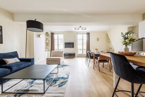 Relax in this stylish living space with a sofa, armchair, and dining table, offering a view of the outdoors.
