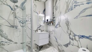 Ein Badezimmer mit einer Duschkabine, einem weißen Waschbecken und einer Toilette.
