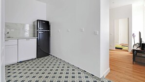 Eine moderne Küche mit weißen Schränken, einem schwarzen Kühlschrank und Fliesenboden mit Muster.
