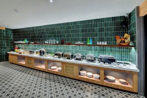 A buffet setup with various food items and utensils. - THE LUXANT HOTEL (Bengaluru)