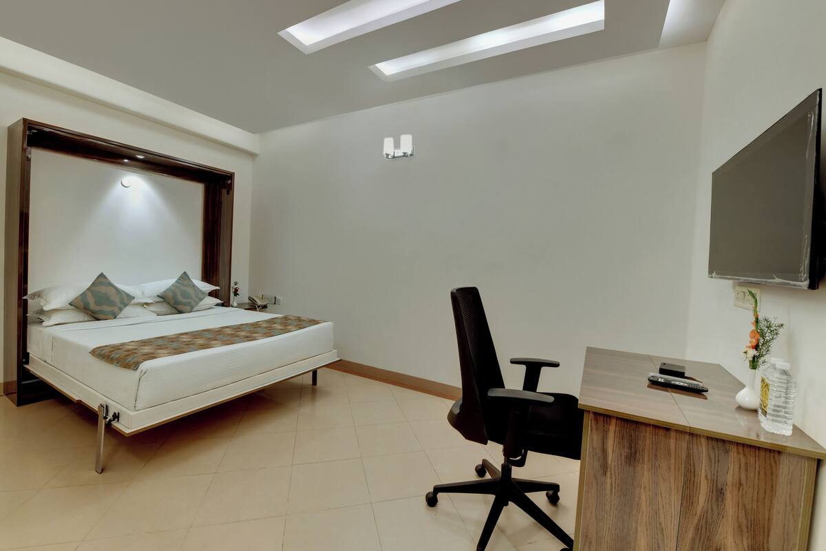 A hotel room with a bed, a desk, and a TV.