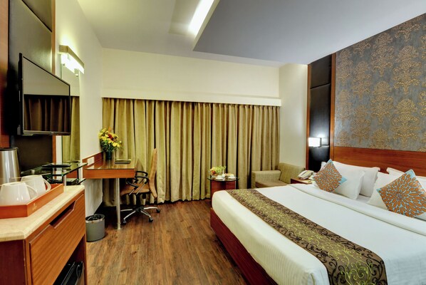 A hotel room with a bed, desk, chair, and a television.
