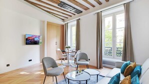 Un salon moderne avec des poutres en bois, un coin repas et de grandes fenêtres.