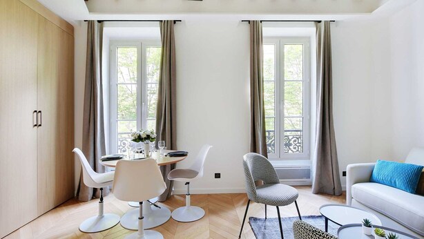 Un salon moderne avec un coin repas, de grandes fenêtres et un plafond en bois.