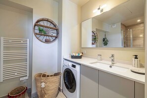 A modern bathroom with a built-in washing machine, a large mirror, and a white sink. - Quiet and luxurious studio - Cannes Center - 2p (Cannes)