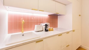 Una cocina moderna con armarios blancos, un salpicadero rosa y un horno empotrado.