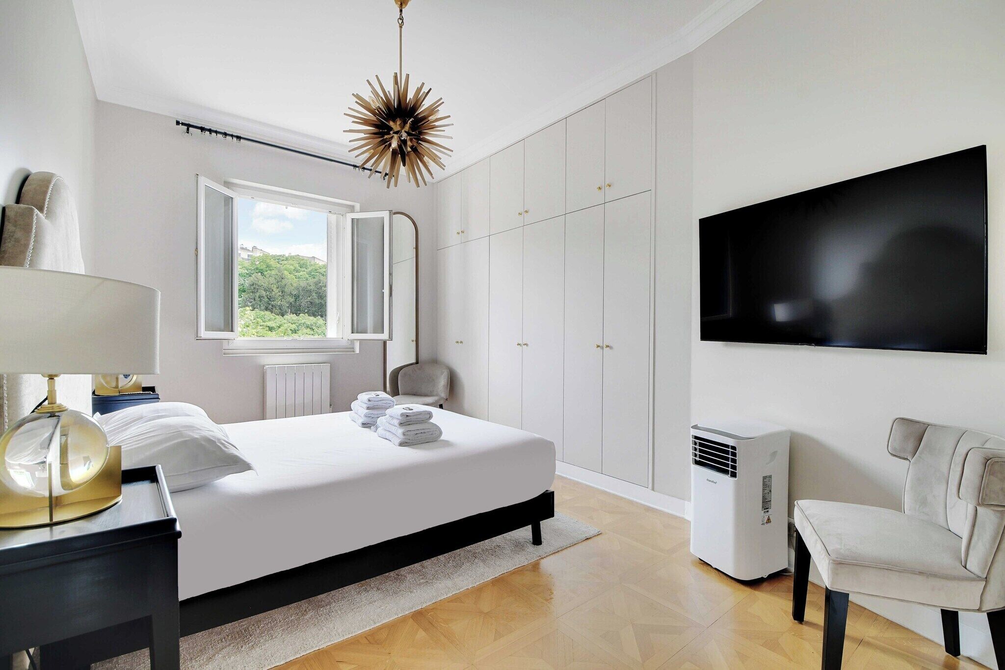 Ein modernes Schlafzimmer mit einem Bett, einem Fernseher, einem Sessel und einer Heizung.