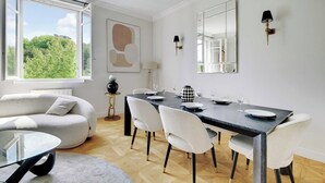 Un comedor con una mesa dispuesta para cuatro personas, un sofá y vistas a zonas verdes.