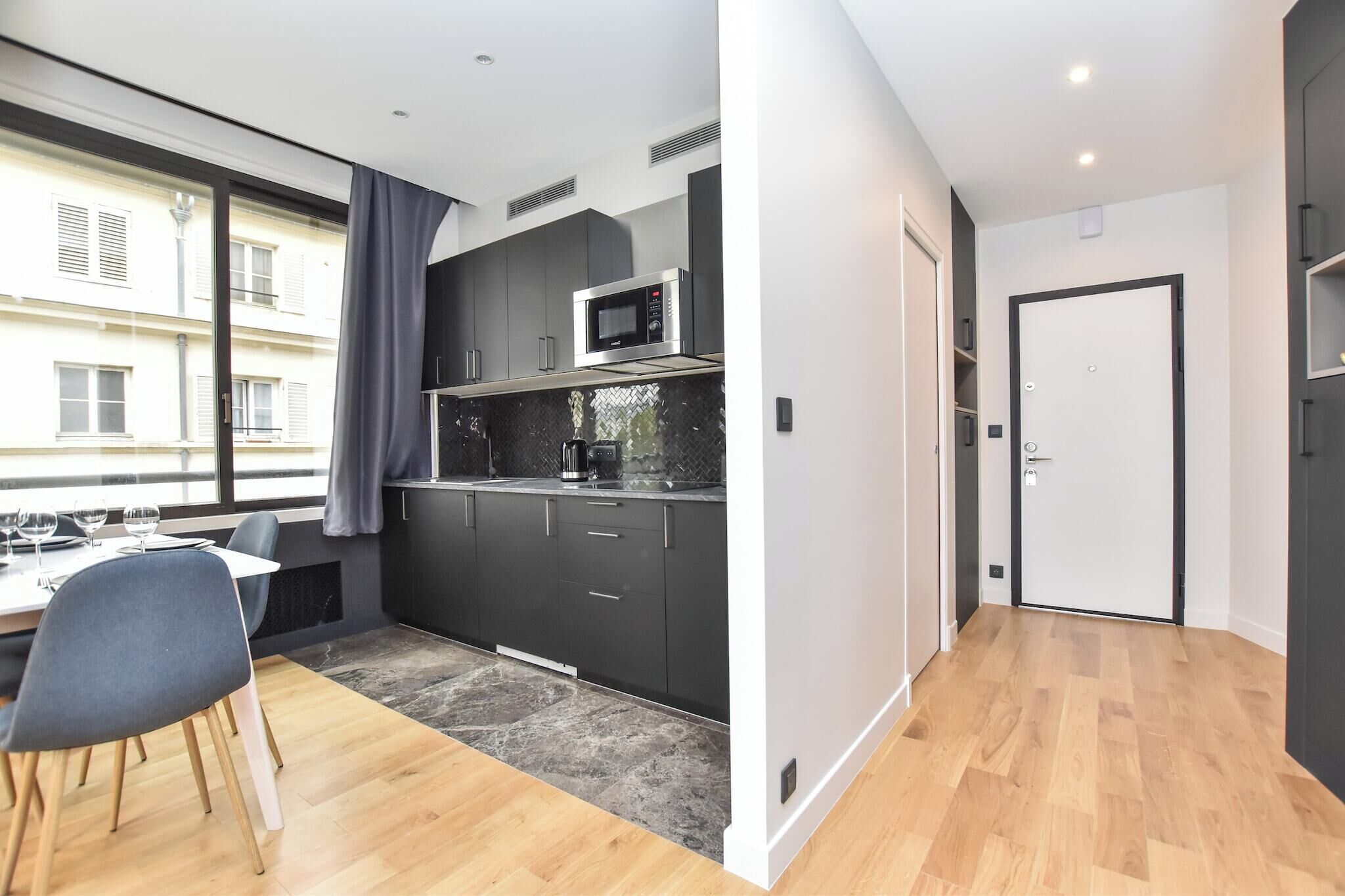 A modern kitchen with dark cabinets, a microwave, and a dining area with a table and chairs.