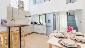 A modern kitchen with a central island, bar stools, and a dining area set for four.
