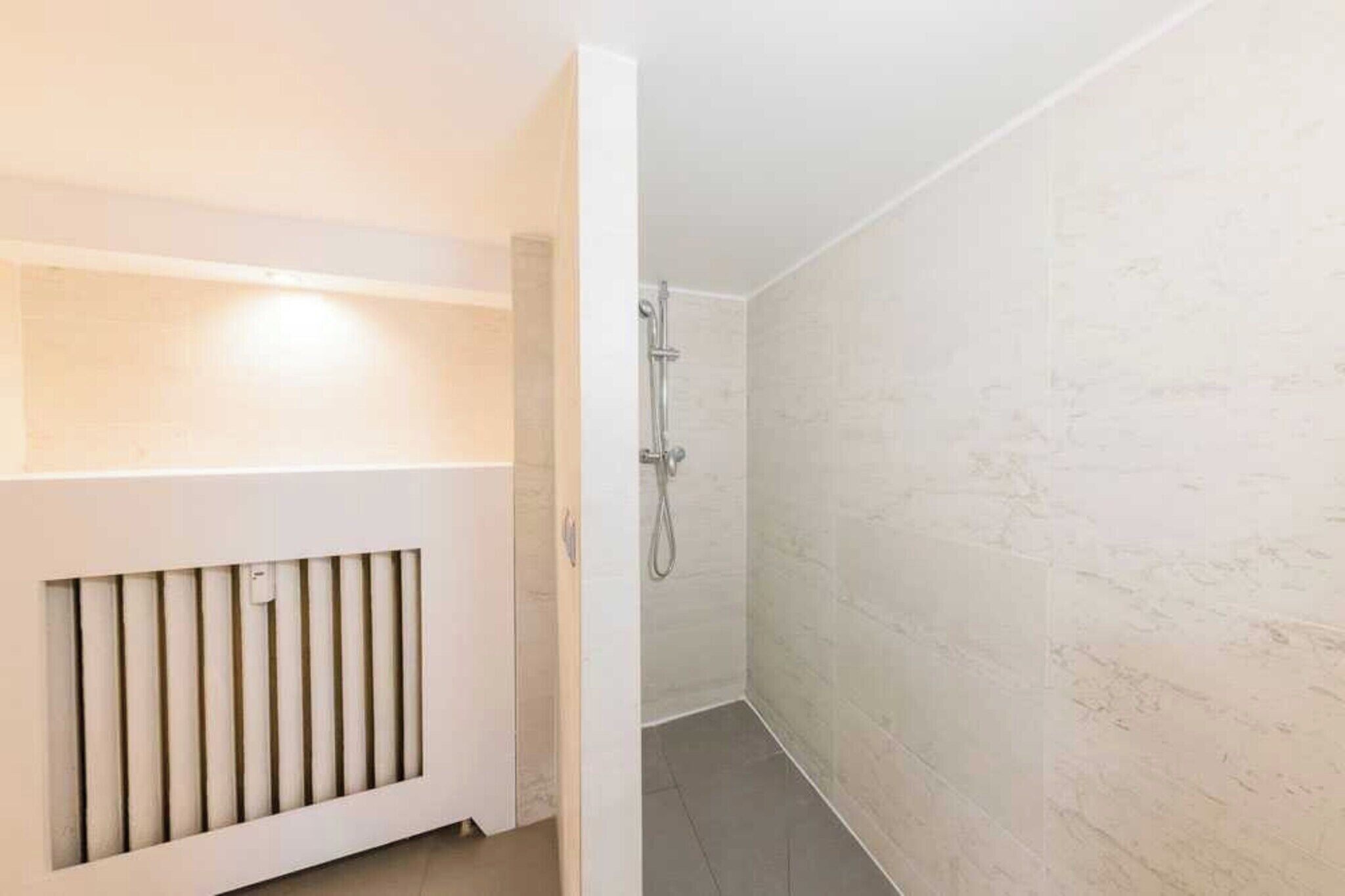 Un baño con ducha, radiador y paredes de azulejos.
