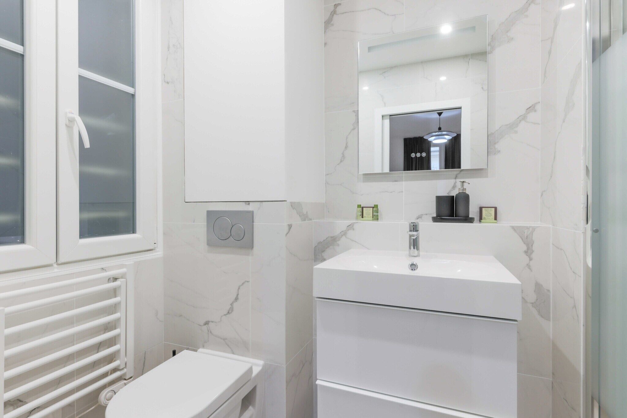 Une salle de bain moderne avec un lavabo blanc, un miroir et des toilettes.