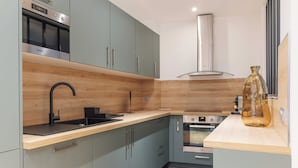 A modern kitchen with grey cabinets, a black faucet, a stainless steel oven, and a wooden countertop. - Magnificent apartment - 4BR/10P - Arc de Triomphe (Paris)