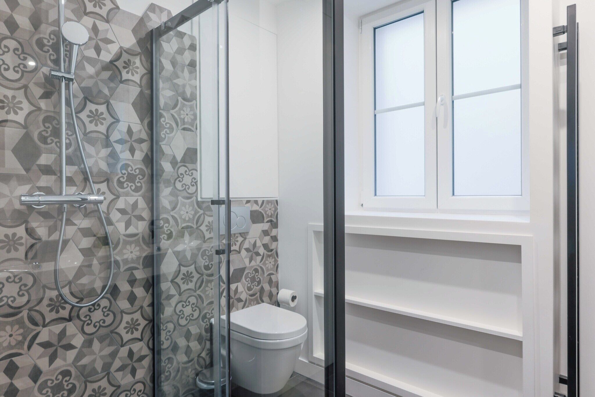 Une salle de bain avec une douche, des toilettes et une fenêtre.