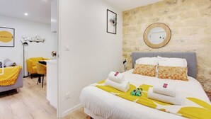 A hotel room with a bed, a desk, a chair, and a mirror on the wall.