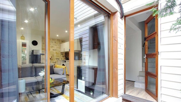 A modern living room with a glass door leading to a kitchen, a sofa, and a coffee table.