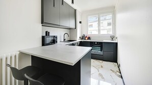 A modern kitchen with a central island, dark cabinetry, and a window providing natural light.