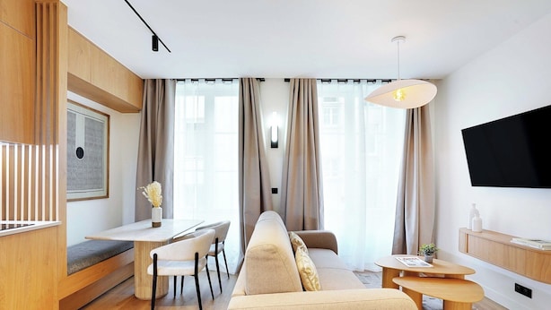 Una sala de estar moderna con un sofá, una mesa de comedor y un televisor montado en la pared.