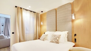 Una habitación de hotel moderna con una cama grande, un cabecero de madera y una zona de estar con una silla.