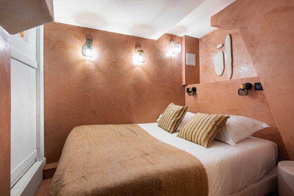 Relax in a spacious room with a large bed, nightstand, and wall-mounted light fixtures.