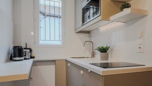Una cocina moderna con horno empotrado, un lavamanos y una ventana con rejas.