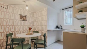 Una cocina moderna con una mesa redonda, sillas verdes, un papel tapiz estampado y una ventana.