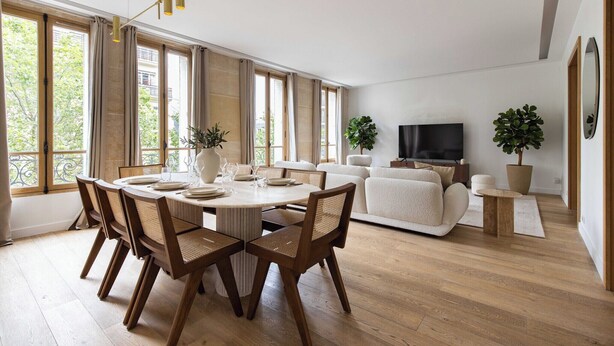 Una sala de estar moderna con comedor, ventanas amplias y televisor de pantalla plana.