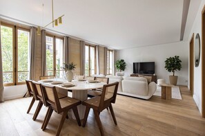 A modern living room with a dining area, large windows, and a flat-screen TV. - Sublime Apt - 3BD/6P with AC - Victor Hugo/16e (Paris)