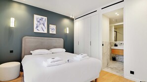 A modern bedroom with a large bed, bedside tables, and a walk-in closet.